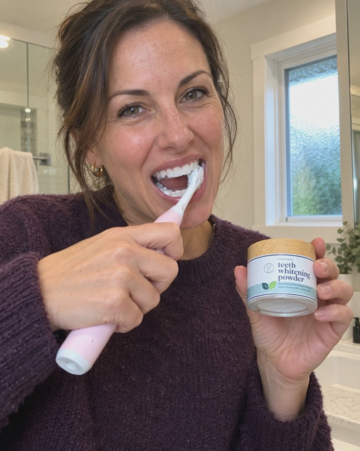 Mujer cepillándose los dientes con el polvo blanqueador