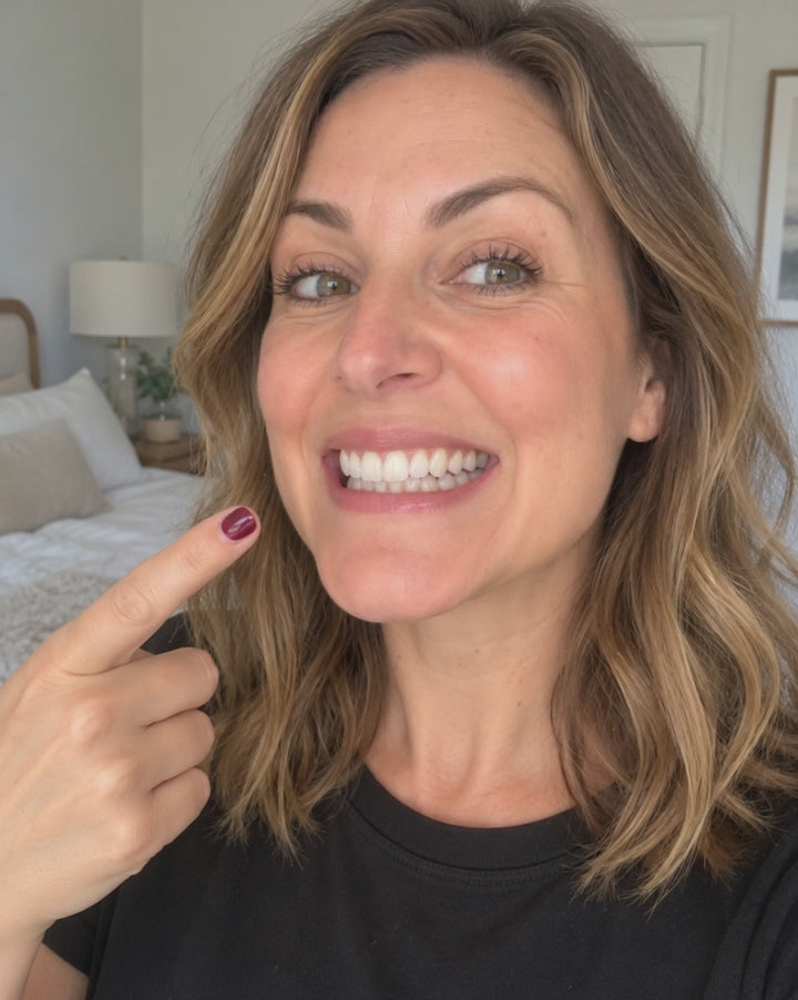 Mujer sonriendo y señalando sus dientes