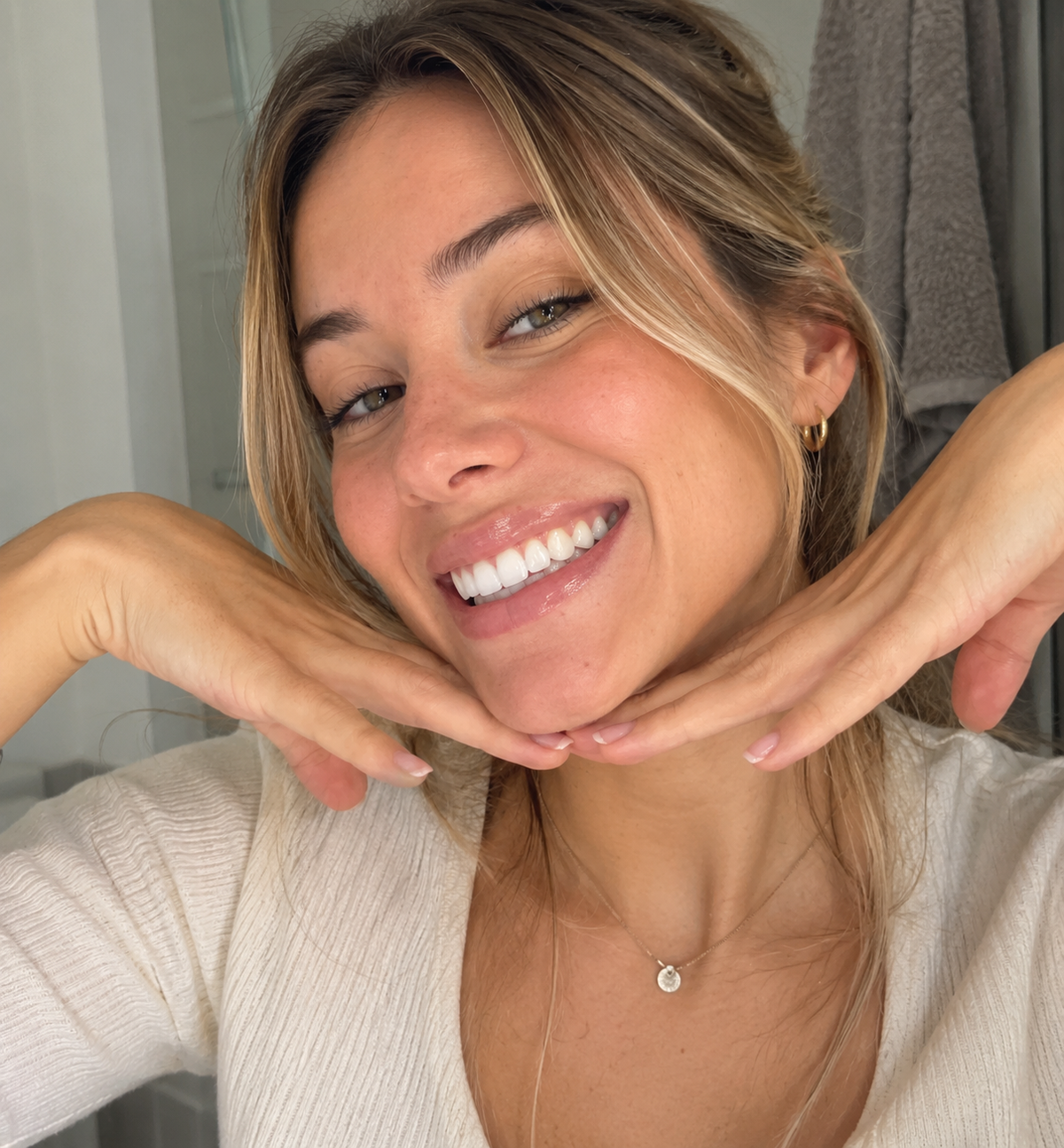 Mujer sonriendo con las manos bajo la barbilla